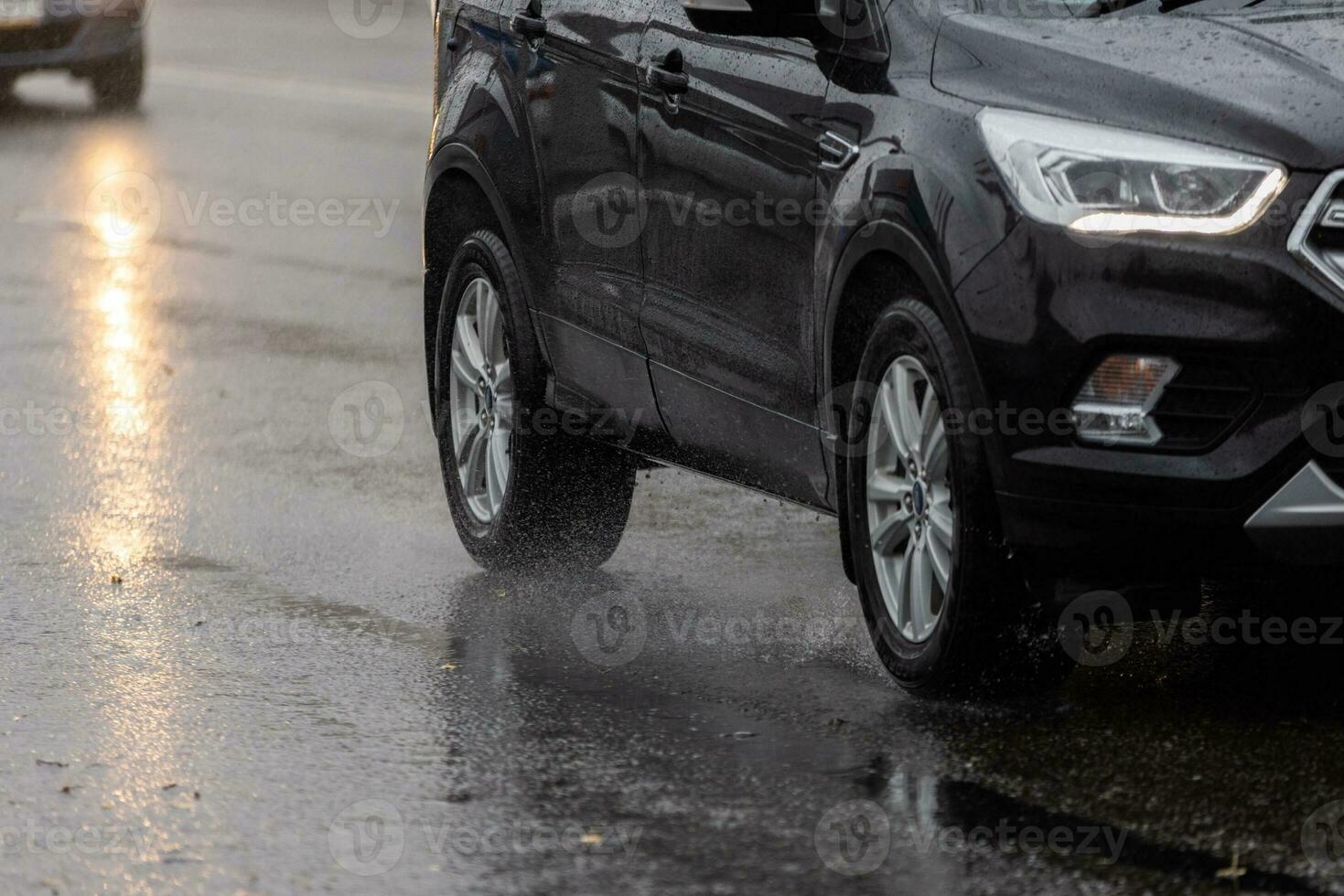 fluxo de respingos de água da chuva das rodas do carro preto em movimento rápido na cidade à luz do dia foto