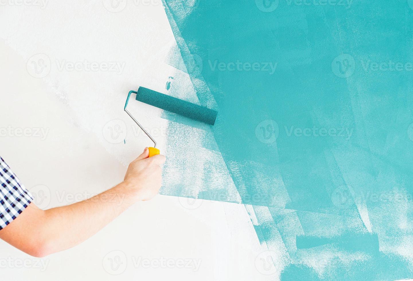 homem colorindo parede azul com um rolo foto