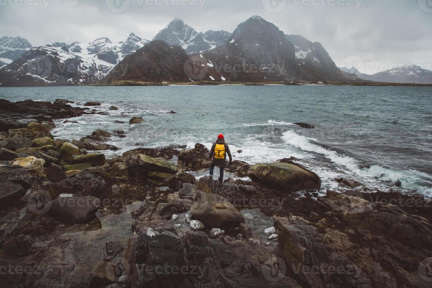 fotógrafo viajante nas rochas contra o fundo do mar e da montanha foto