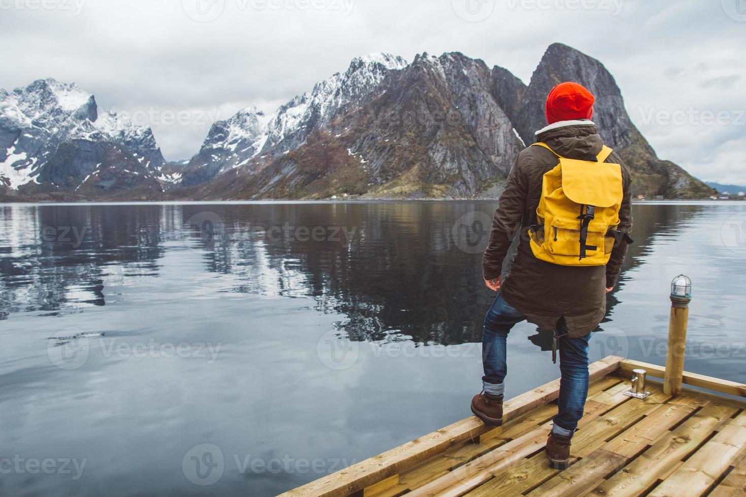 homem viajante parado no fundo do cais de madeira da montanha e do lago foto