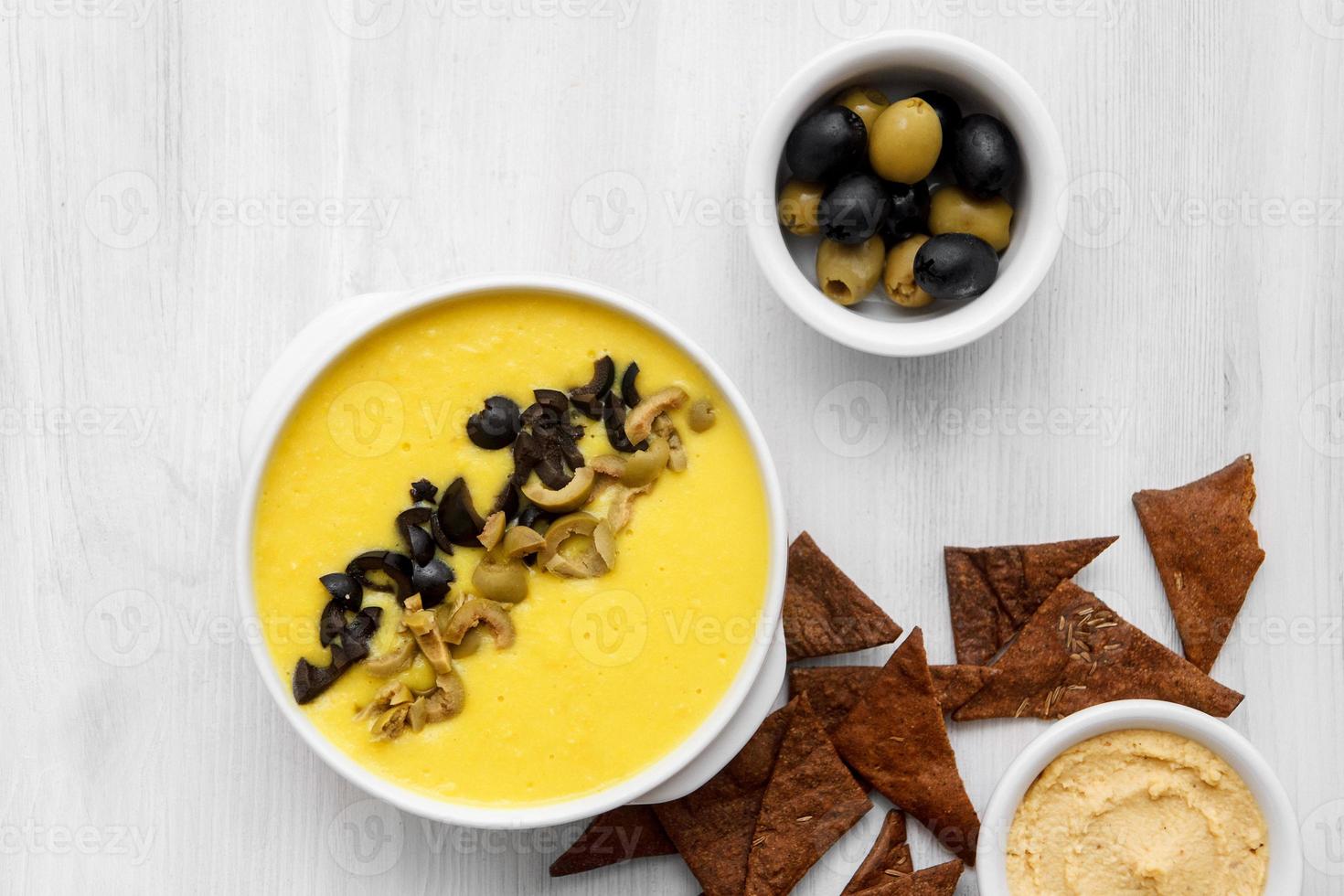 sopa de legumes com azeitonas e biscoitos em um fundo branco foto