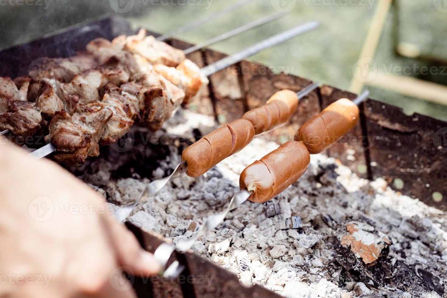 close up de kebabs em espetos, homem grelhando carne ao ar livre foto