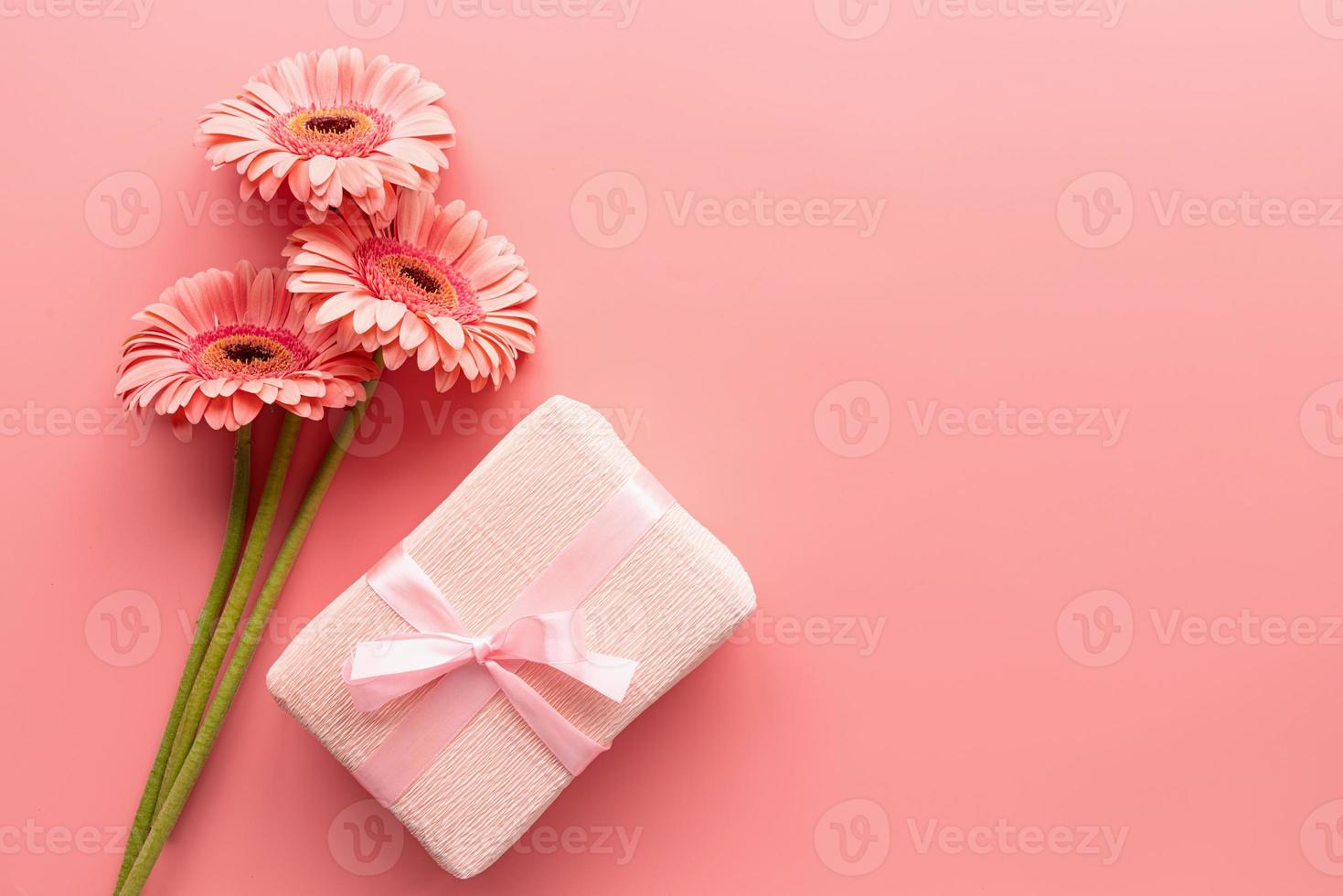 buquê de margaridas gerbera rosa e presente rosa em um fundo rosa foto