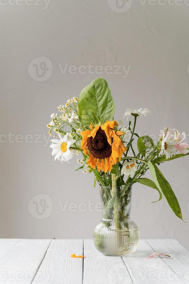 um buquê de flores secas murchas em um vaso branco foto