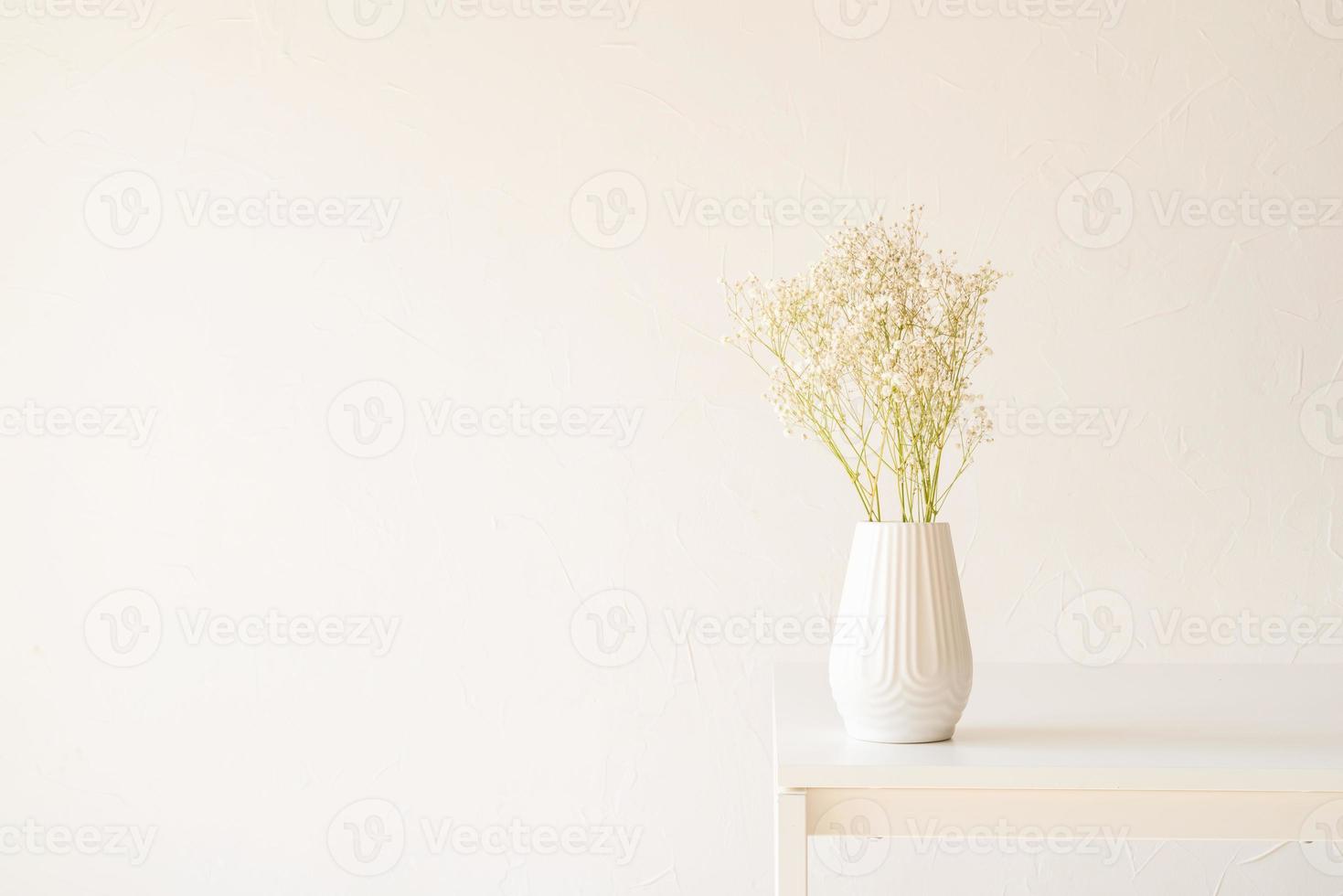 flores brancas de gipsófila em um vaso branco sobre a mesa, estilo minimalista foto