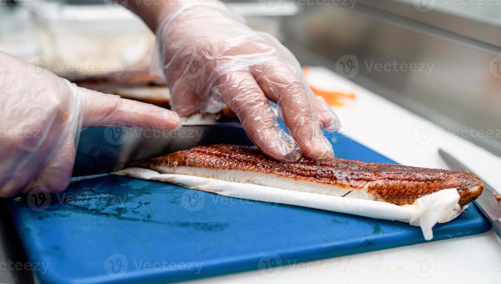 chef de sushi fatiando peixe foto