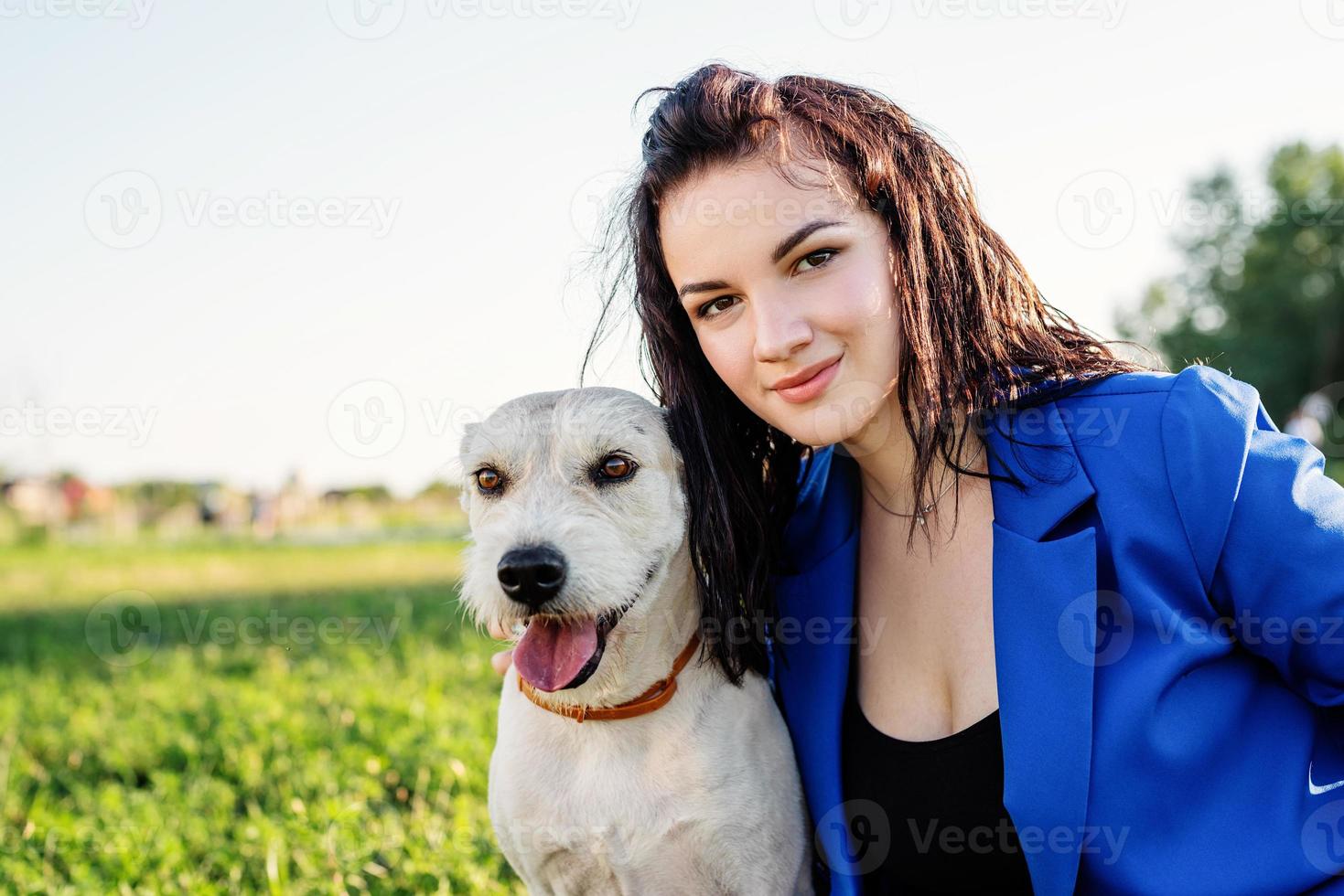 bela jovem sentada na grama abraçando seu cachorro no parque foto