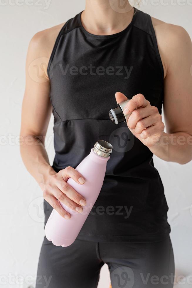 perto de uma mulher com as mãos segurando uma garrafa térmica foto