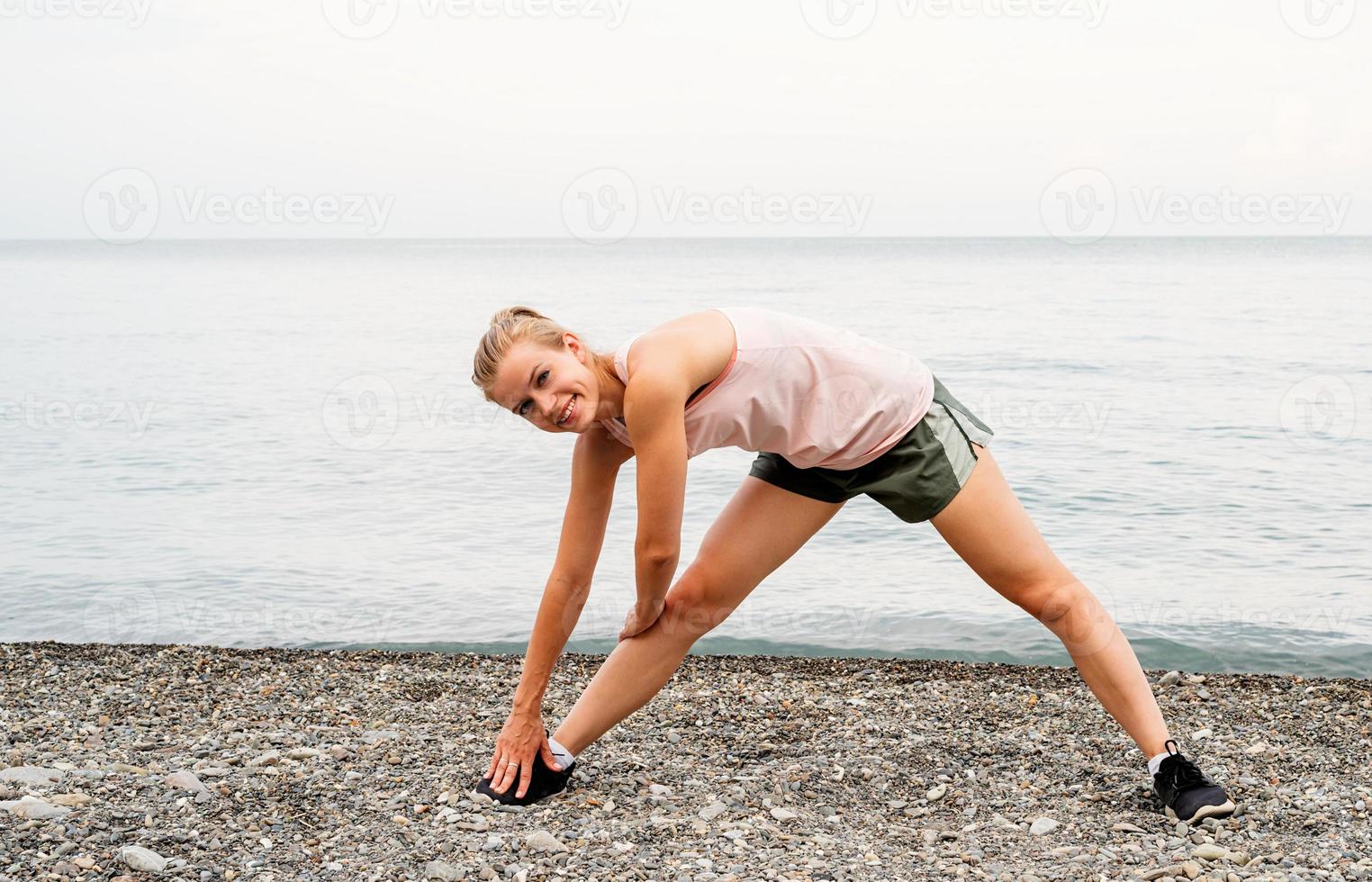 mulher atleta blong fazendo exercícios na praia foto
