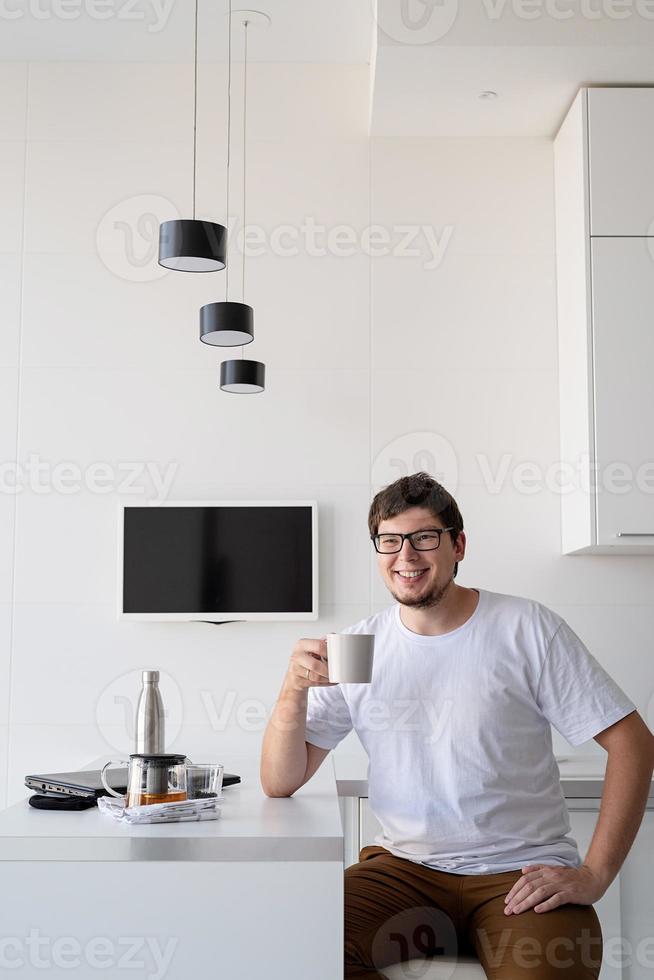 jovem feliz tomando café da manhã em casa, pensando foto