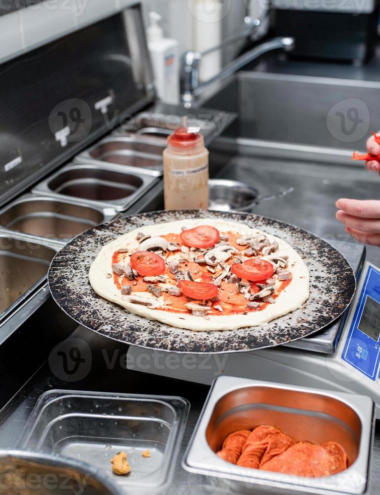 padeiro fazendo pizza na cozinha da pizzaria foto