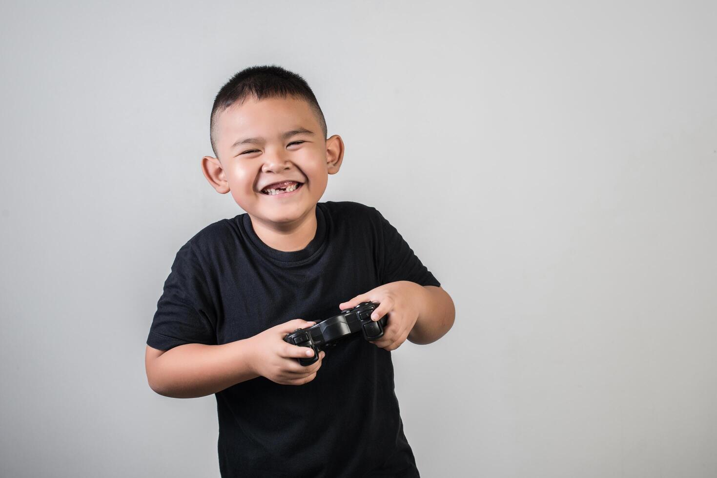 menino feliz jogando computador com um controlador em estúdio foto