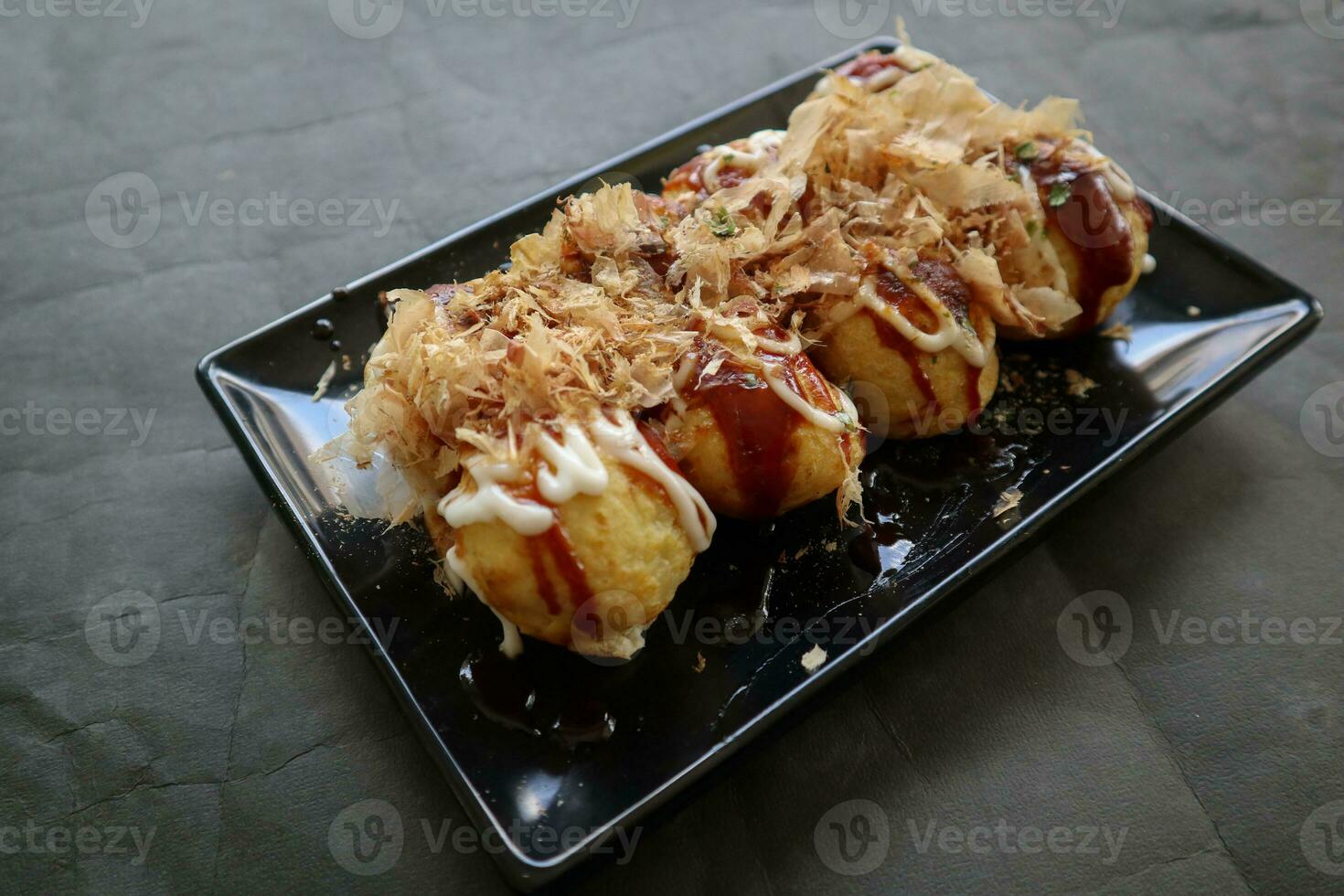 takoyaki é uma japonês comida, fez a partir de trigo farinha massa, polvo carne, ou de outros recheios, servido com molho, maionese e cobertura dentro a Formato do katsuobushi ou madeira peixe aparas de madeira. foto