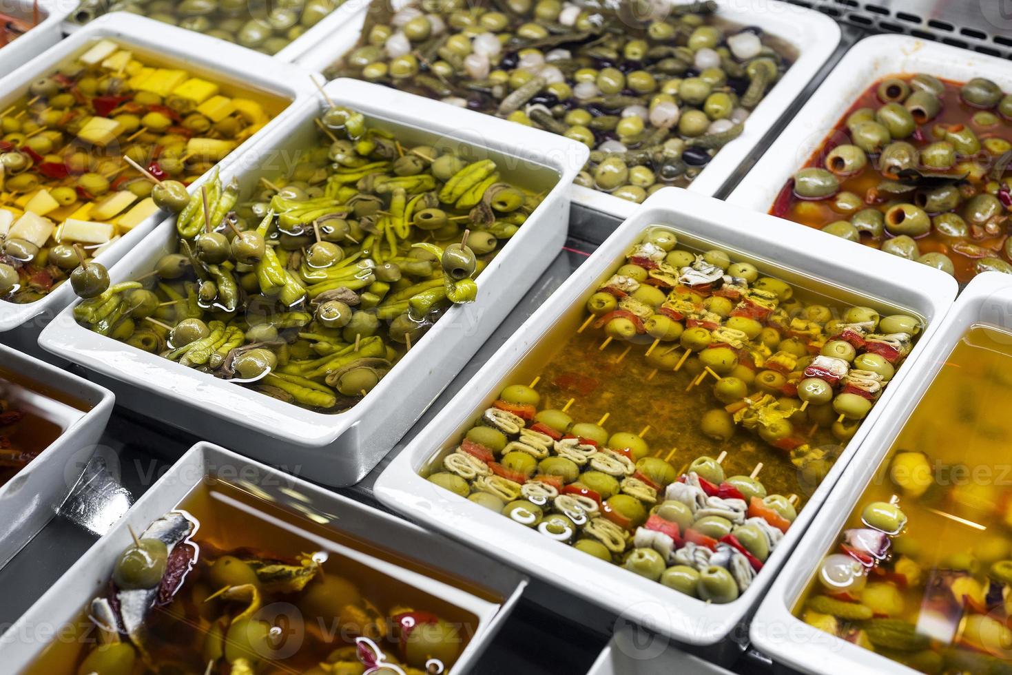 petiscos de tapas com azeitonas mistas no mercado de la boqueria bandejas de exibição em barcelona, espanha foto