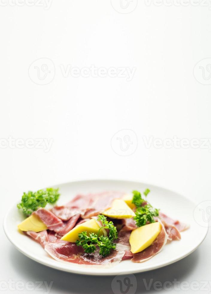 presunto curado parma serrano com salada de manga fresca e salgadinho foto