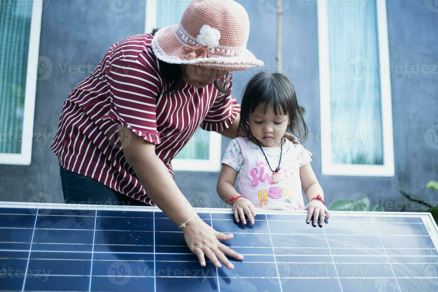 uma feliz ásia família admira a solar painéis elas somente instalado às seus lar. foto