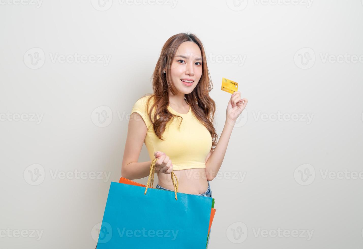 retrato de uma mulher bonita segurando uma sacola de compras e um cartão de crédito foto