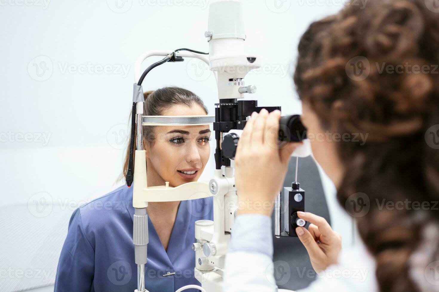 médica oftalmologista está verificando a visão do olho de uma jovem atraente na clínica moderna. médico e paciente na clínica de oftalmologia. foto
