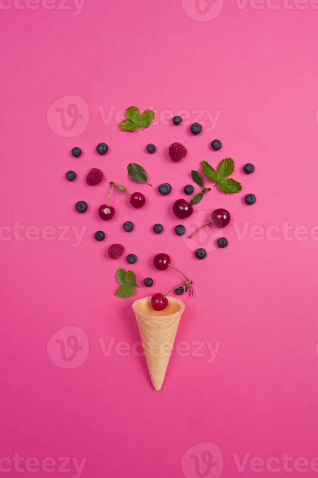 cereja fresca com cone waffle no fundo rosa. conceito de design. foto