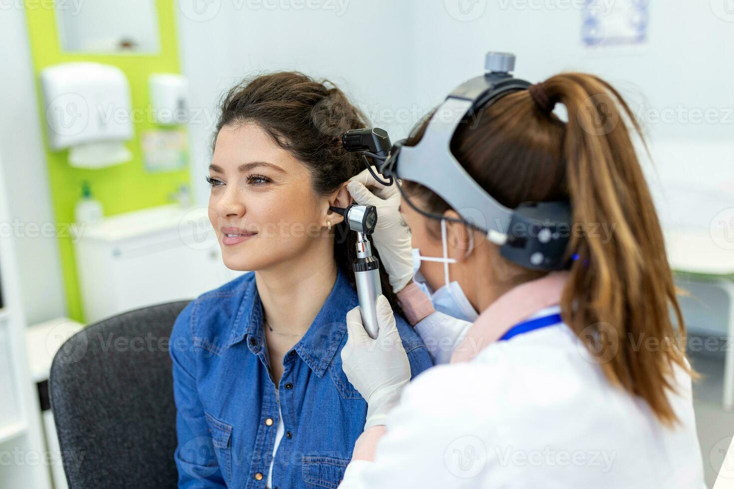 audição exame. otorrinolaringologista médico verificação mulher orelha usando otoscópio ou auriscópio às médico clínica. otorrinolaringologista puxar orelha com mão e olhando às isto com otoscópio fechar-se. foto