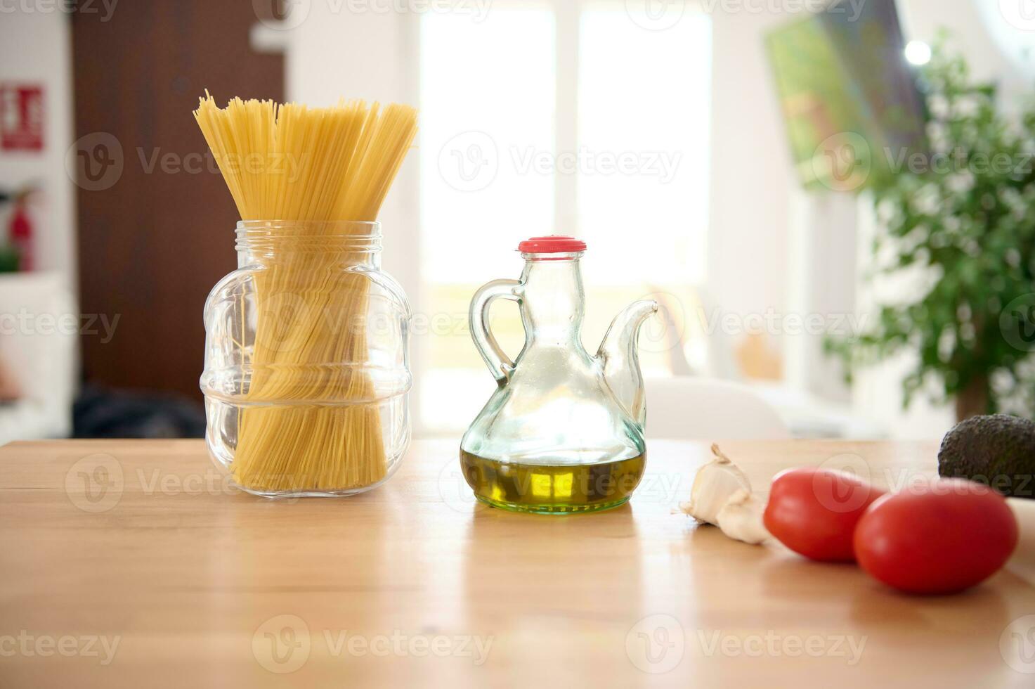 ainda vida. uma vidro lata de óleo do fresco extra virgem Oliva óleo, italiano espaguete e tomates em a mesa dentro casa cozinha. foto