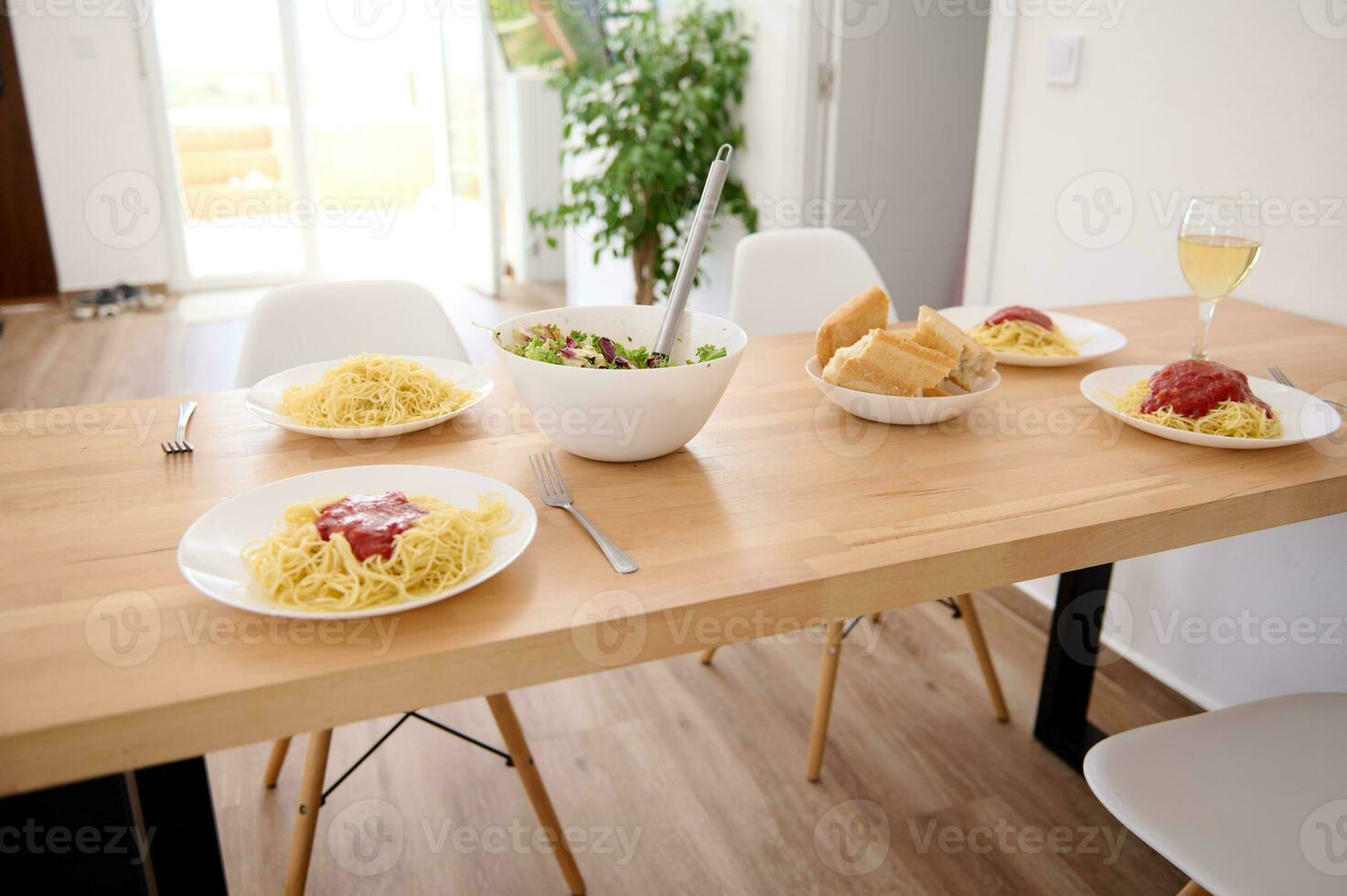 italiano espaguete com fresco tomate molho e uma tigela do fresco saudável vegano salada, servido em uma de madeira mesa dentro a casa foto