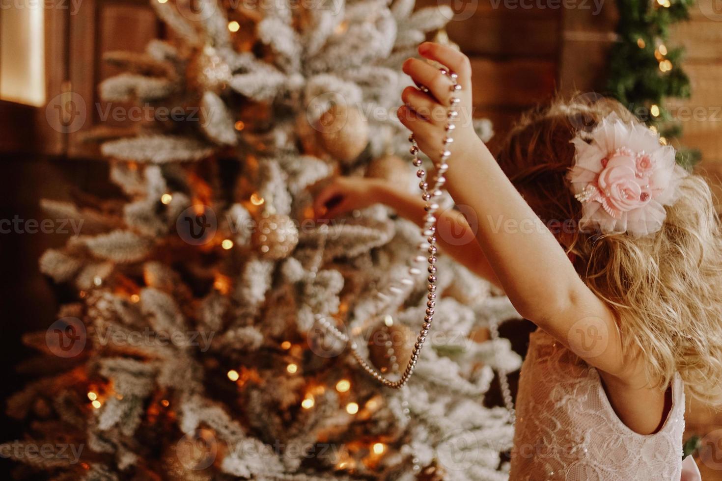 menina decora a árvore de natal com miçangas foto