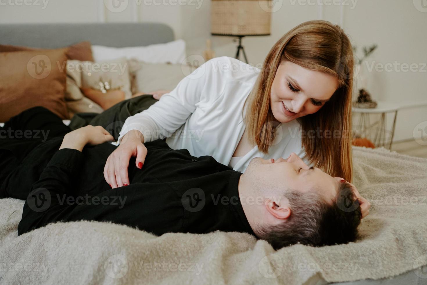 casal muito amoroso na cama. eles estão se abraçando e sorrindo foto