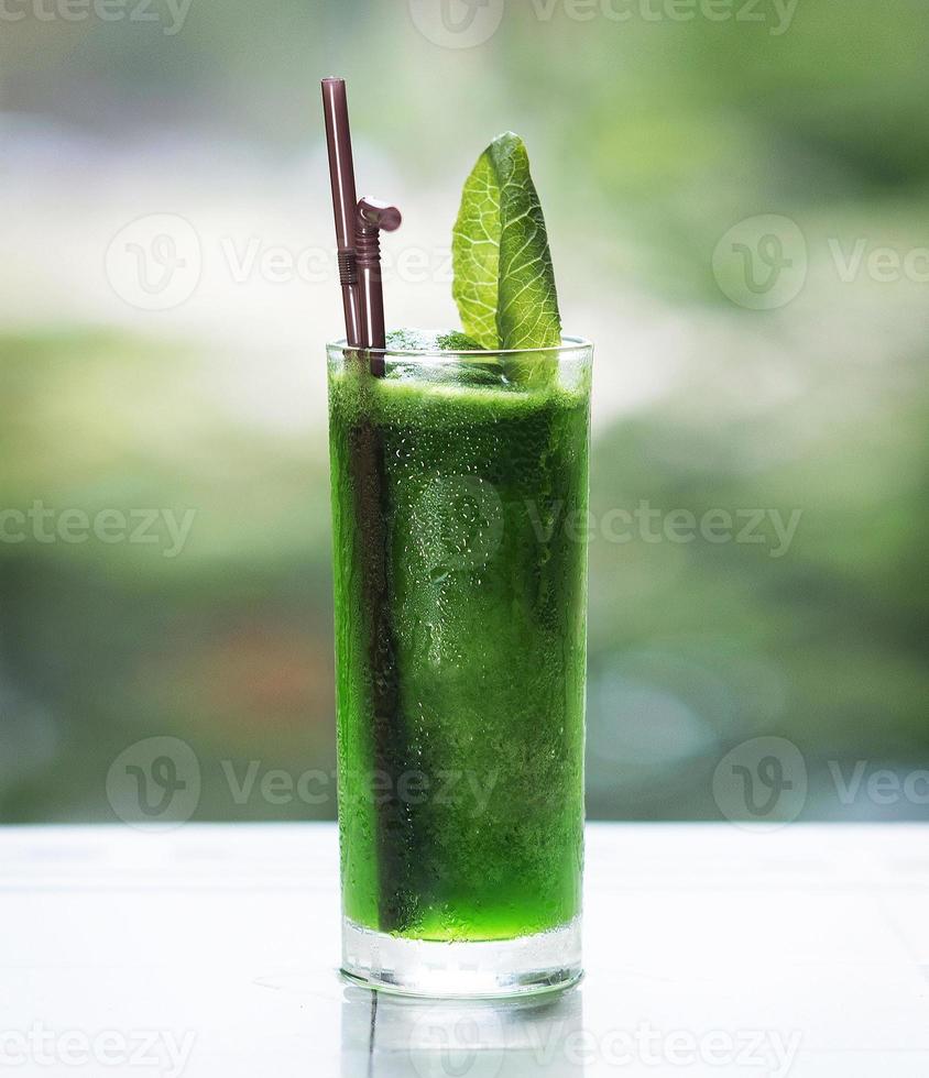 Suco desintoxicante orgânico fresco de folhas verdes escuras em copo alto feito com couve, pepino, alface e espinafre foto