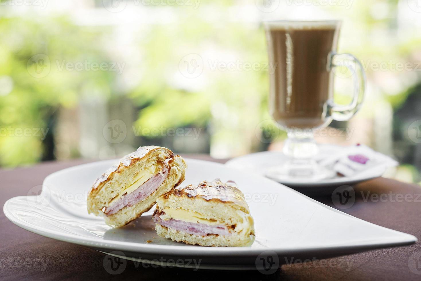 sanduíche em um prato branco e café no fundo foto