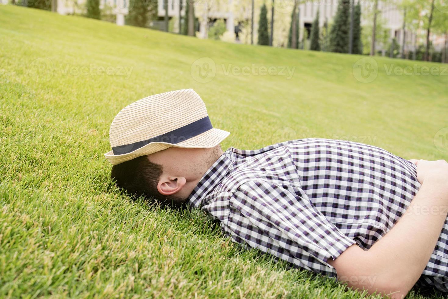 jovem pensativo sentado na grama do parque foto