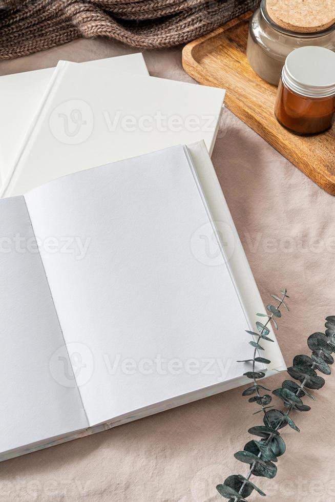 livro aberto, velas e vista superior das folhas de eucalipto. mock up design foto