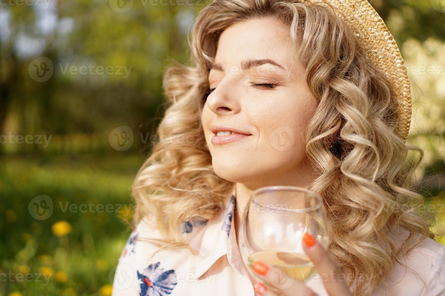 loira feliz segurando uma taça de vinho branco foto