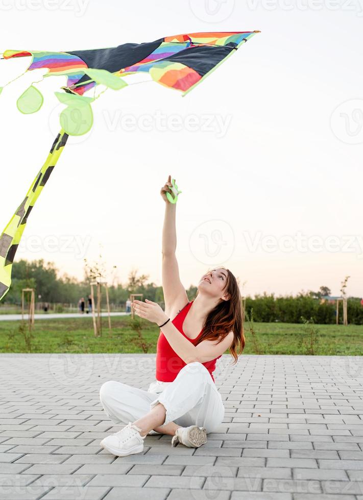 jovem empinando uma pipa em um parque público ao pôr do sol foto