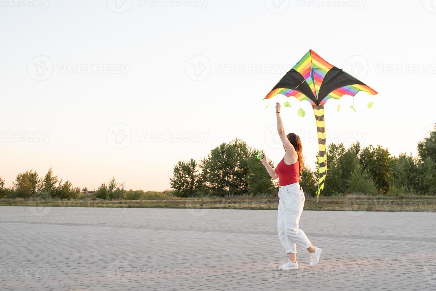 jovem empinando uma pipa em um parque público ao pôr do sol foto