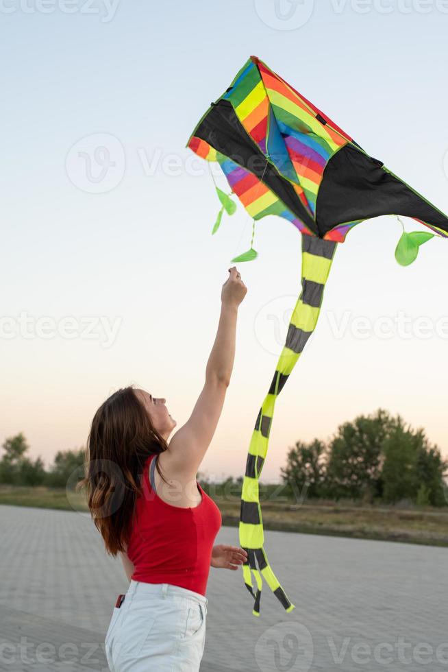 jovem empinando uma pipa em um parque público ao pôr do sol foto