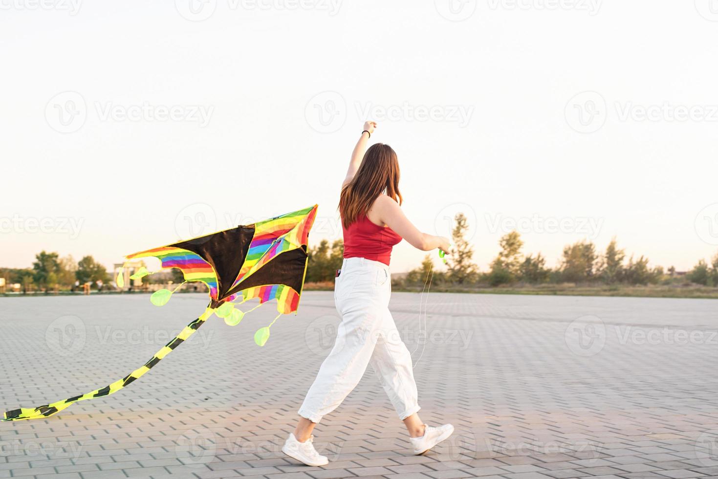 jovem empinando uma pipa em um parque público ao pôr do sol foto