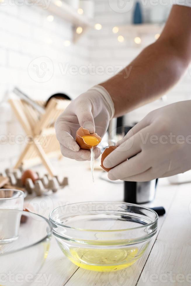 mãos do homem separando a gema e a clara da casca do ovo na cozinha foto