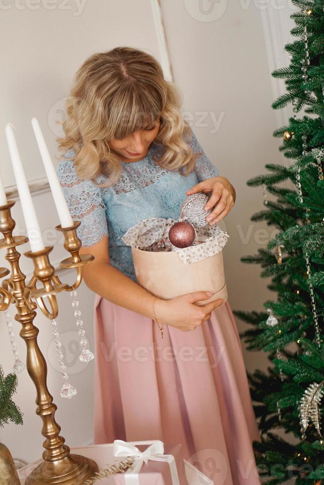jovem decora a árvore de natal com brinquedos de natal foto