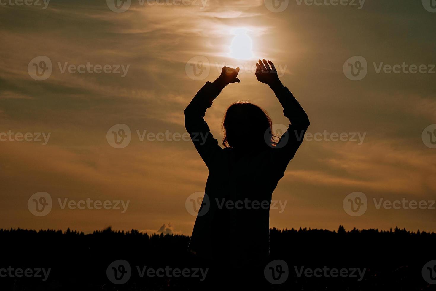 mulher apreciando o pôr do sol. silhueta feminina no campo ao pôr do sol foto