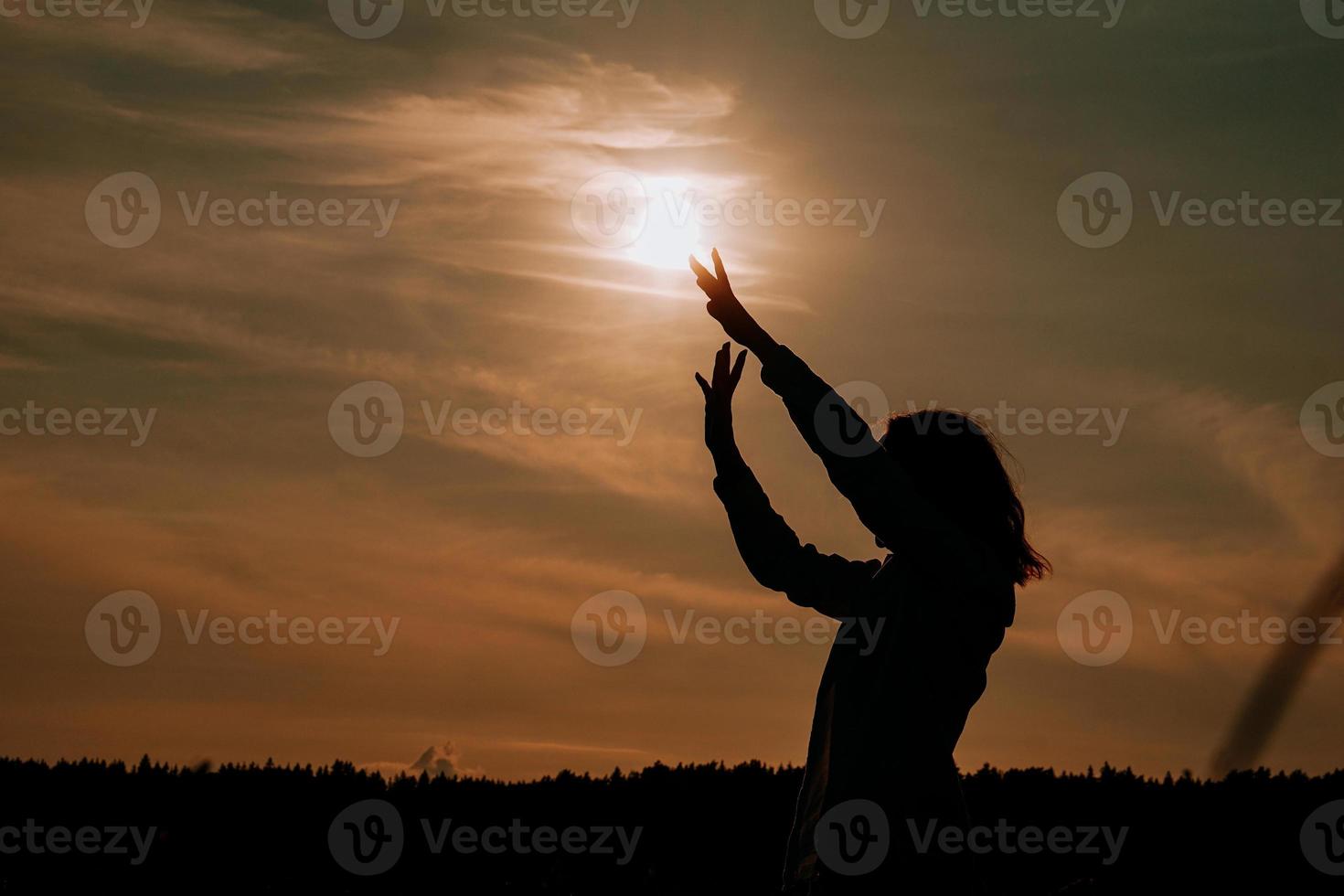 mulher apreciando o pôr do sol. silhueta feminina no campo ao pôr do sol foto