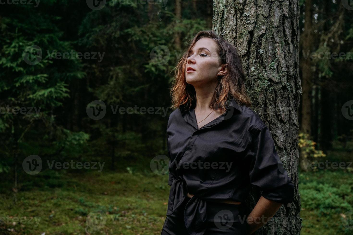 jovem - fechar retrato em uma floresta escura. mulher de camisa preta foto