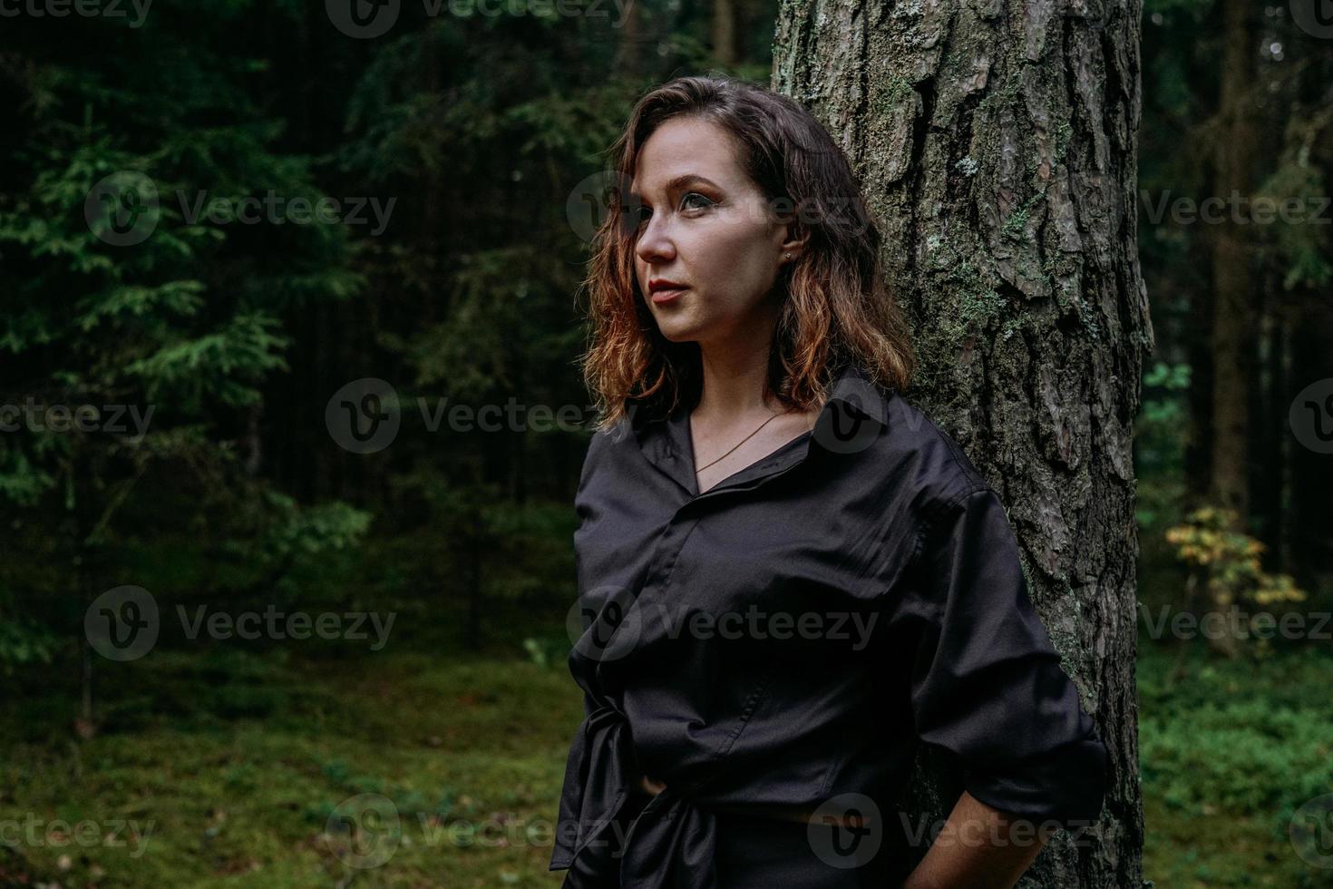 jovem - fechar retrato em uma floresta escura. mulher de camisa preta foto