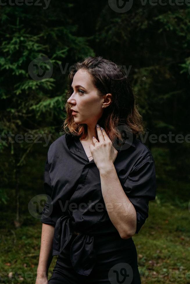 jovem - fechar retrato em uma floresta escura. mulher de camisa preta foto