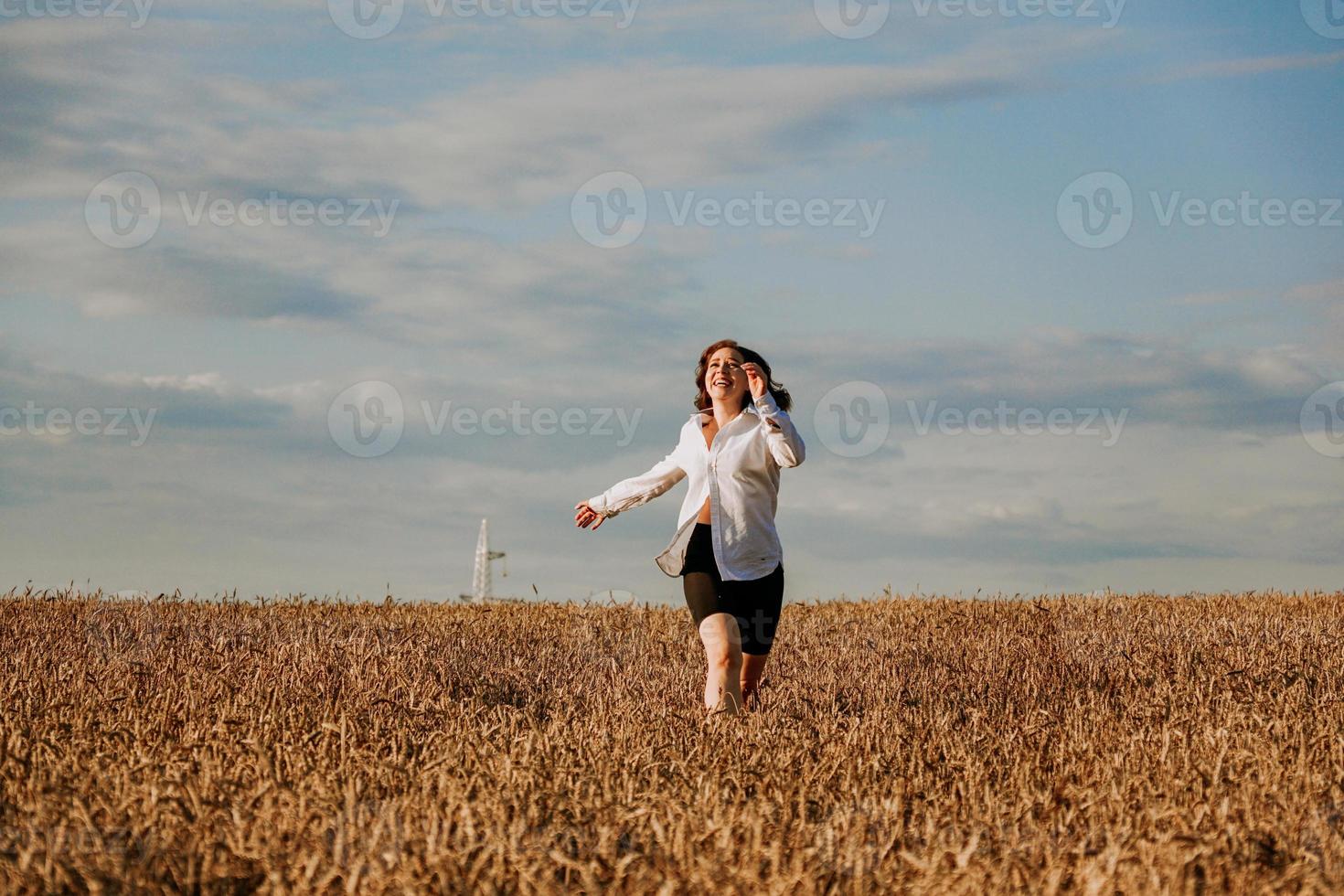 mulher corre em um campo de trigo em um dia de verão. conceito de felicidade e alegria foto