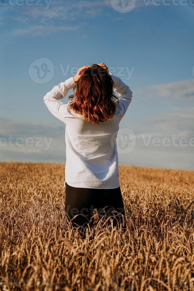 mulher no campo de centeio. vista de trás. o conceito de harmonia foto