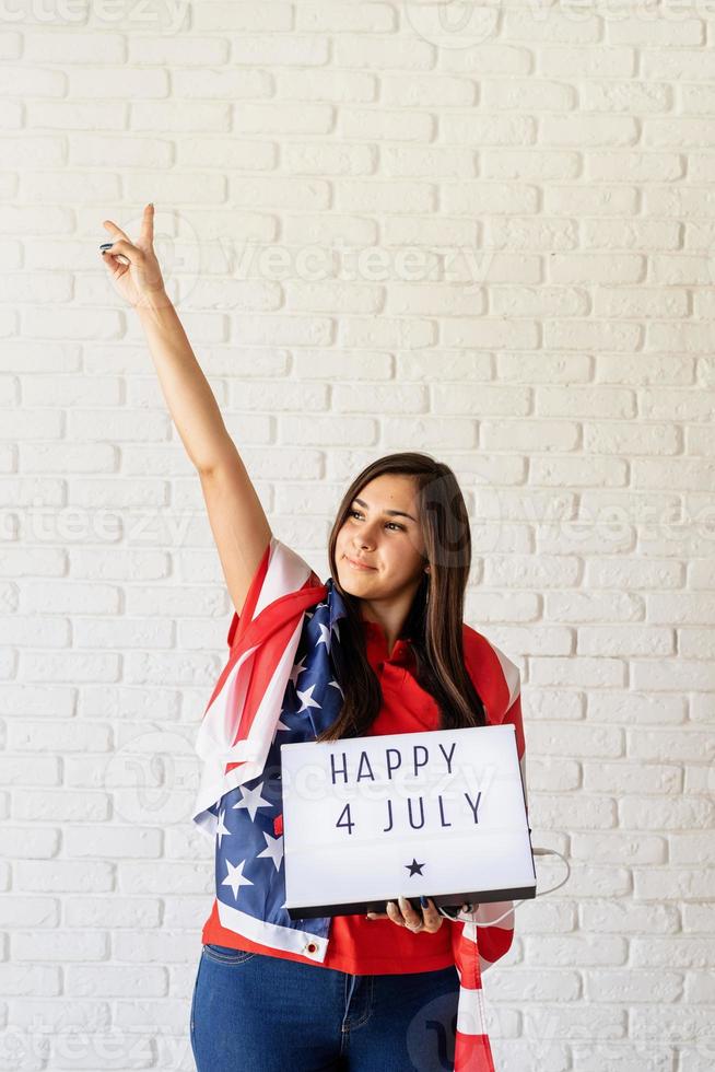 mulher com bandeira americana segurando mesa de luz com palavras feliz 4 de julho foto