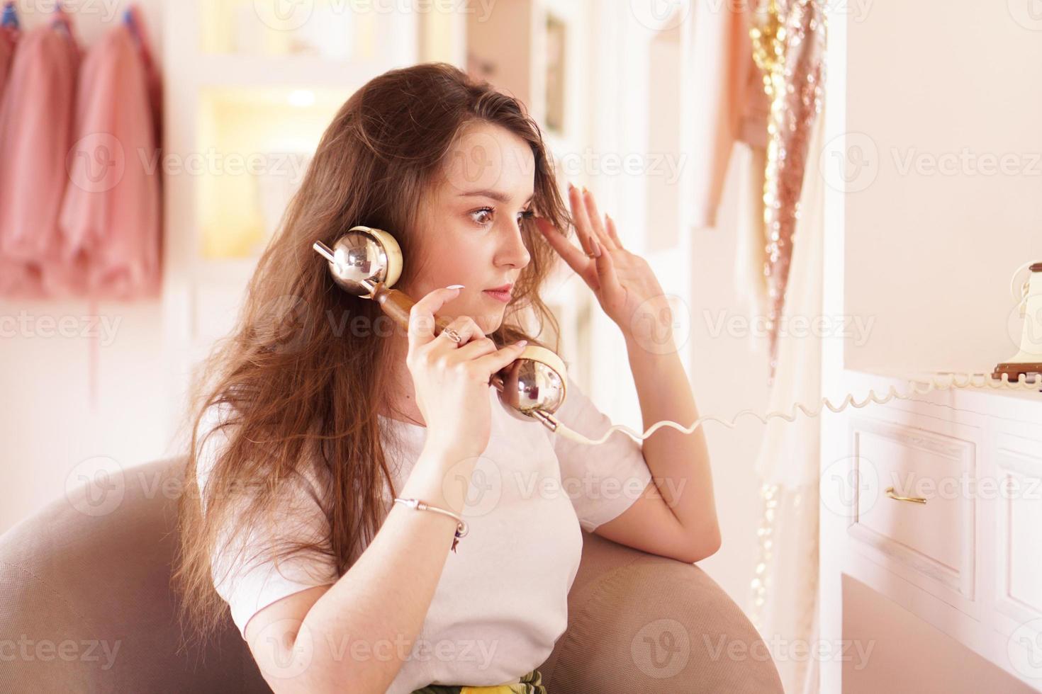 uma mulher surpresa fala ao telefone. aparelho de telefone em estilo retro foto
