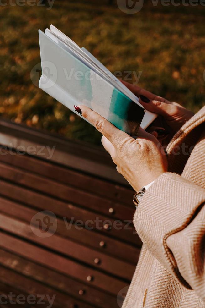 mulher com um casaco de outono segura um livro. parque de outono foto