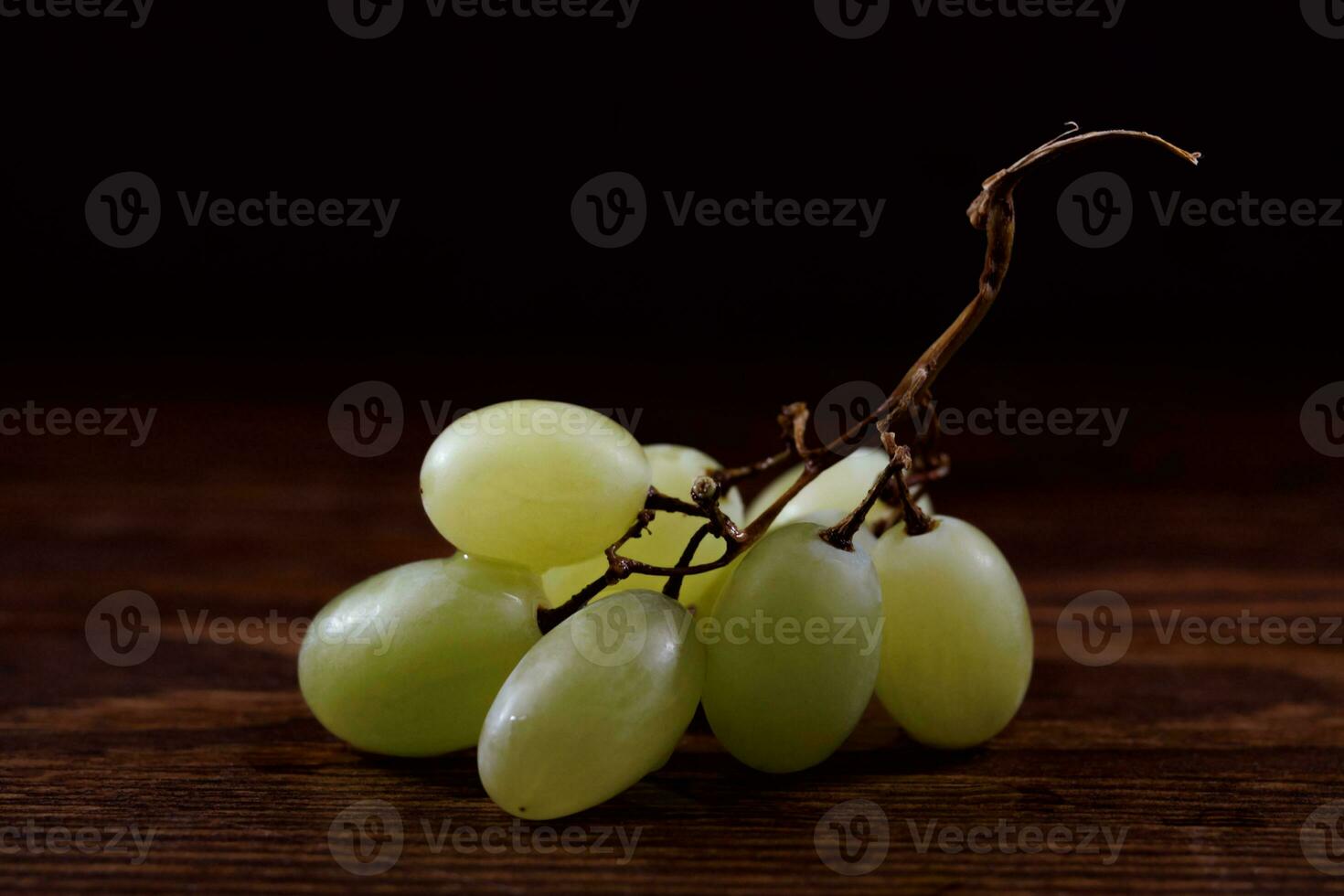 uma pequeno grupo do maduro verde uvas em uma de madeira borda. foto